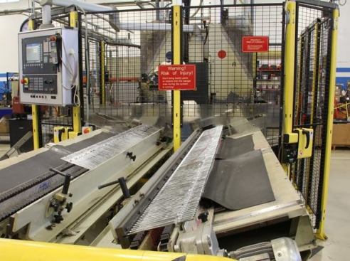 There are more steps to making screwdrivers than I would have thought. The line of silver pieces running front to back in this photo are screwdriver shafts after stamping and plating (the same kind you saw in the previous photos). They’re being conveyed to the machine inside the cage for final grinding.