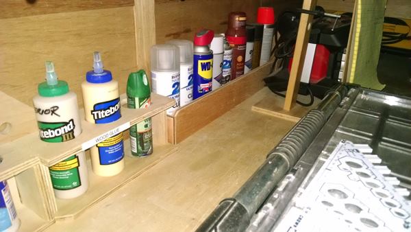 Wood glue and aerosols store in purpose-built slots along the back edge of the work bench.