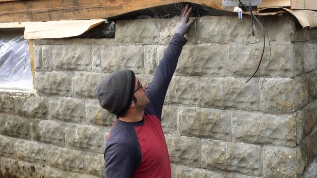 Mark Pollard explains the treatment of the home’s foundation sill during early winter. The bituminous peel-and-stick membrane, inserted between the existing foundation block and the existing wood sill, would later be integrated into the wall system’s Grace Ice and Water Shield air barrier above. But during the blower door test, it became apparent that some air was infiltrating the block walls and entering the basement at the gap between the wall’s interior rigid foam insulation and the spray-foam-insulated band joist area. During blower door testing, Pollard filled that gap with canned foam insulating sealant.