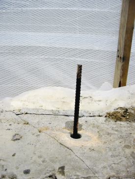 Strands of epoxy-coated rebar pin the repositioned upper wall to the undisturbed portion below grade.