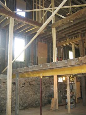 The floor framing was removed in sections and interior bracing installed to stabilize the walls; tall posts supported the floor system above.
