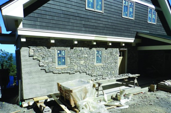 Working from the top down (so all the mortar that might fall off the trowel or the back of the stone would fall harmlessly to the ground without creating a mess on the face of the stone below), the mason could start installing the stone veneer. We selected material, from Stoneyard.com, that is consistent with the natural stone in the area. We specified a mix of 80% Ledge Stone and 20% Mosaic.