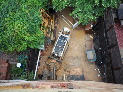 To remove the dirt, the crew uses a conveyor belt that dumps into a stand-on skid steer 