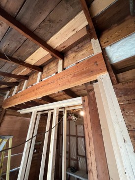 A column was framed into the wall to support the right-side end of the new beam. Note the new cripple studs bearing on the new beam to beef up support for the old porch roof as well as the main house roof. 