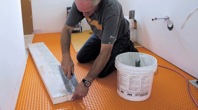 With both matching Kerdi-Board faces pre-coated with mortar, Boucher adds more mortar to one of the faces and tools it to the proper depth using a special Kerdi trowel with one-eighth-inch notches.