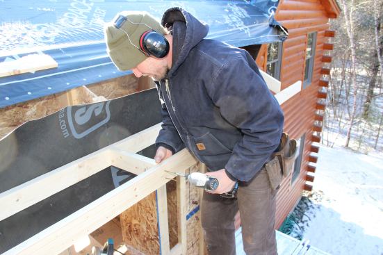 In Greenwood, Maine, forty miles from the coast, builder Jesper Kruse finishes the eave on a superinsulated ski-lodge addition. The air-barrier fabric between the eave outrigger ladder and the wall of the house to Kruse’s right will connect with fabric wrapping down the roof and fabric coming up the wall, completing an airtight control layer around the high-performance building shell.
