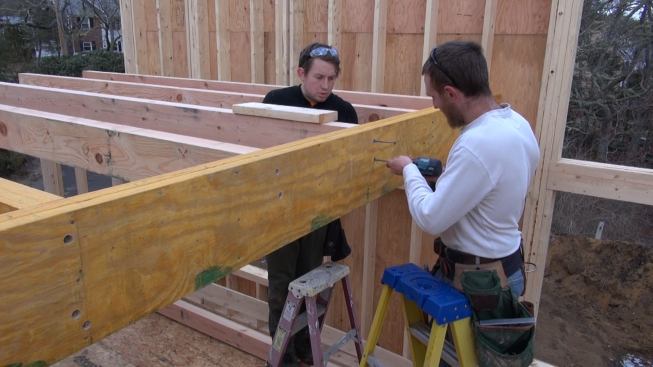 Hill sets the screws for another joist while Laffin holds the floor joist to its layout line.