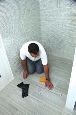 On a curbless shower, the simplest configuration is to locate the drain at the transition to the bathroom floor. 