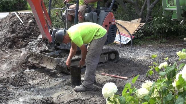 A crew member spins the top coupling off the well casing, prior to inserting the geothermal heat exchange tubing for the heating and cooling system’s ground loop.
