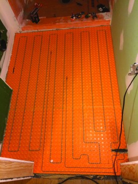 With the bathroom in the middle of the house, there was no need to tie it into the home's heating system. Instead the tile floor is warmed with a heat mat. The wall-hung fixtures meant a simple rectangular layout for the mat.