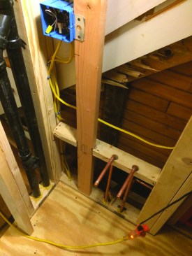 The bathroom was situated away from any existing plumbing, so the toilet vent was installed in the narrow wall next to the sink (pipe on the right). The drain and vent for the sink (pipe on the left) fits into the same wall, with the vent joining the toilet vent above.