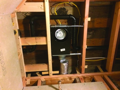 After some creative routing around the light fixture, the vent line makes its way through the ceiling framing and joins the shower vent.