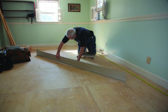 Using an 8-foot aluminum straightedge,the author checks the plywood subfloor for flatness. Any low spots will telegraph into the flooring. This particular spot isn't low enough to warrant repair.
