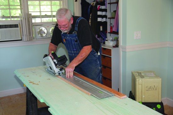 A track saw with the blade set at a slight angle cuts close to the scribe line. The saw's dust collection system minimizes the mess in the finished room.