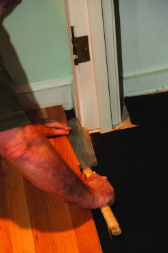 Where the flooring met the doorway of a closet, the casing trim was cut back using a scrap of flooring as a height gauge.The jamb is kept intact, but the stop is trimmed off as well.
