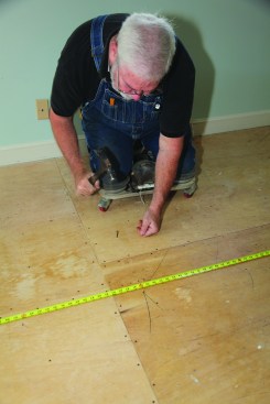 After locating and marking the floor joists, the author drives special screw-nails through the subfloorand into the joists.