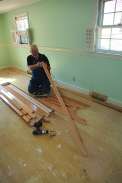 The flooring strips for the starter course must be perfectly straight. The author sights down enough pieces for the first row. 