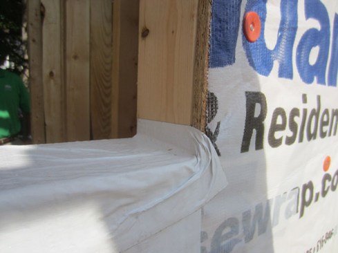 I prefer using a flexible sill flashing, which allows the critical corners to be formed easier and increases the chances of the sill flashing staying flat. On a recent project, I compromised and allowed the builder to install straight flashing, applying it with a 1-inch lap onto the jamb (without cutting the corner). Flat flashing tape tends to retract when being applied to two disparate planes because of its relatively rigid polyethylene backing. Going up only 1 inch, the corner was difficult to achieve, but it was passable—albeit with some wrinkles.