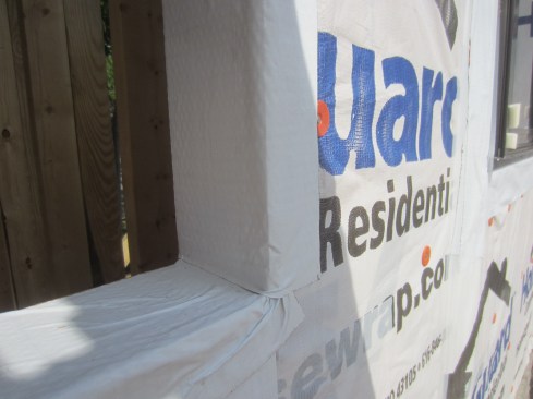 Jamb flashing. For the jamb flashing, I recommend installing a straight peel-and-stick flashing adhered to the housewrap on the face and to the wood in the rough opening. Where the jamb flashing laps the sill flashing, the lap is not perfect (there are still wrinkles) but it is sufficient; any water that finds its way to the flashing will “shingle off.” Once the jamb flashing is in place, the window is installed with the flanges caulked (just not at the sill) and fastened to the wall.