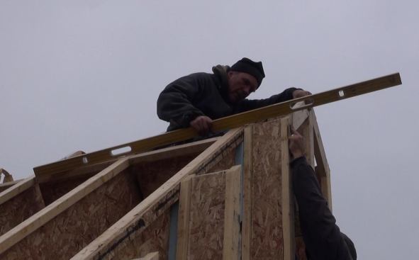 Todd places blocking at the roof peak, using a six-foot level to keep the block in plane with the I-joist rafters.