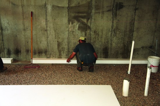 After compacting and raking the stone base perfectly flat, the crew put down 4-inch-thick insulation on top of the perimeter footing.