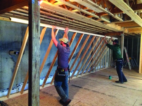 The walls for the finished basement were framed directly on top of the OSB sheathing. Plates were screwed to the sheathing with screws that did not penetrate through to the poly barrier. Photo by Steve Demetrick