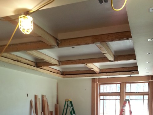 The ceilings in the individual bays and surrounding soffits were drywalled prior to trim installation, and shims were glued and tacked to the underside of the rough beams to establish a level underside for the trim work.