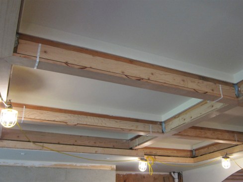 The trim was then secured tightly to the underside of the beams with lengths of shipping strapping, which allowed the author’s crew to fine-tune the trim’s alignment along the A and B axis. The crew used a laser line to shoot through the living room to the dining room to line the grids up.