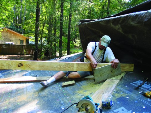 To scribe the roof angle on the ridge, a length of stock is leveled over from the common rafters and a 2-by scrap is set against the sleepers.