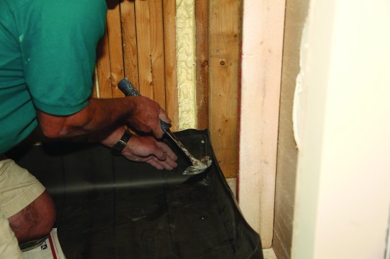 After the membrane is placed in the shower, carefully fold the excess in the corner, keeping it as flat as possible, and secure the folds with a nail at least 2 inches above the threshold.
