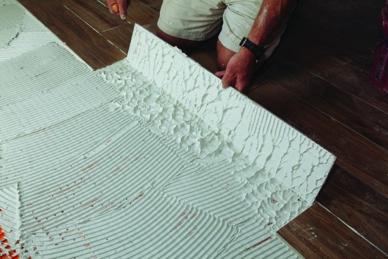 The perpendicular direction of the trowel lines allows air to escape along the long side of the tile as it beds into the thinset. Every few courses, it’s a good idea to lift up a tile and check the coverage of the thinset. For large-format tile, the coverage should be at least 85% for interior applications and 90% for exterior ones.
