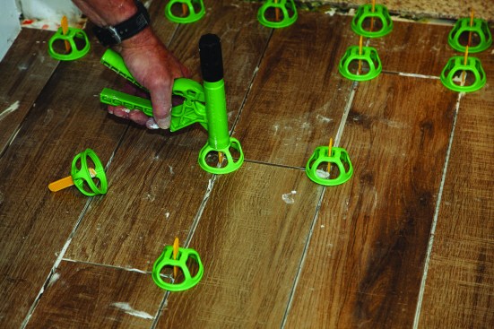 Then he used a proprietary tool to “ratchet” the caps onto the tabs, aligning the intersecting tile surfaces.