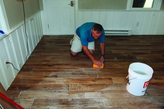 He then went over the whole floor with a wet sponge to loosen and remove any dried thinset stuck on the surface of the tile. A final wipe with the sponge ensured the floor was ready for grout.