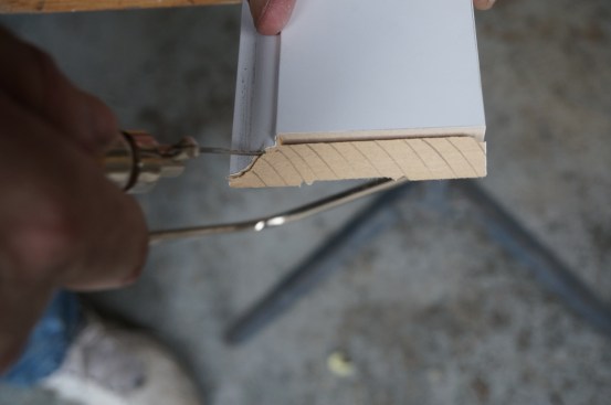 The thin blade of a coping saw follows the curve of the profile at a back bevel angle.
