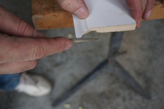 A small round file tunes the edge of the cope so that it follows the profile line precisely.