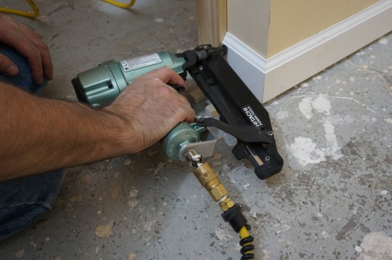 Keeping the corner joint closed and tight, the author drives nails to secure the piece in place.