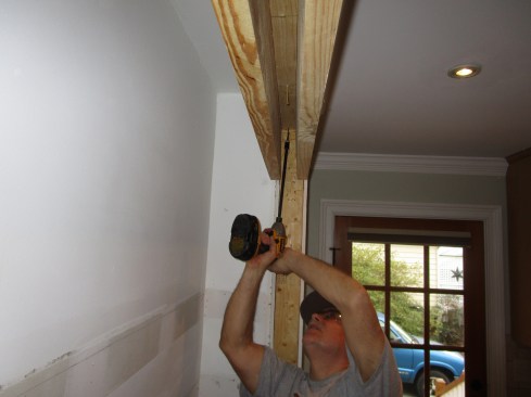 An upside-down-U-shaped header fastens directly to the wall plate above the opening. The space between the sides of the U were filled in with 2-by lumber and plywood. Note that the header for the triple bypass doors is wider than the existing 2x4 walls. The extra thickness was kept to the inside of the pantry, where it was not visible.