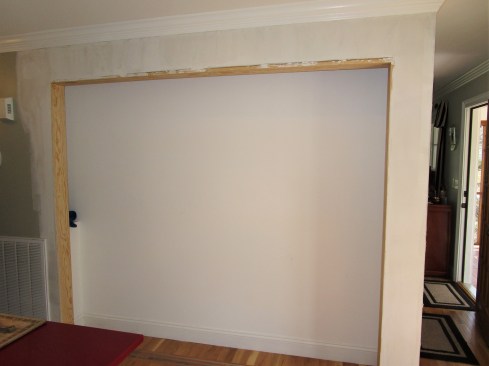 After rough framing the opening, the author installed pine jambs around the opening. He installed the jambs to be flush with the drywall and wide enough to accommodate the three door panels. The header jamb fit tight against the newly installed header to secure the upper tracks that will carry the weight of the bypass door panels.