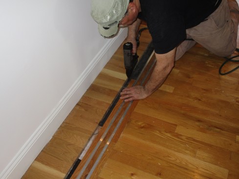 Author installs the guide track on the floor filling in between the tracks with strips of flooring.