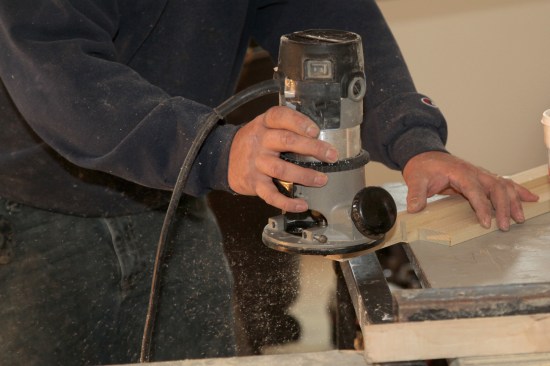 This stool had a simple bullnose (semi-circular) profile along the outside edge. The carpenter uses a round-over bit in a router to complete the profile on the return ends of the stool.