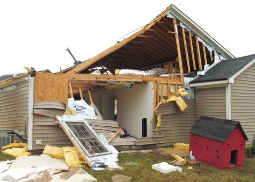 On the opposite side of the house, the foam sheathing at the gable truss is almost completely stripped from the framing. Below, the foam-sheathed portion of the wall was lost, though the OSB corner bracing is still in place.