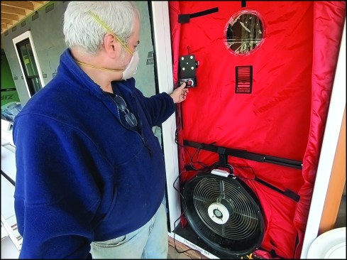 With the blower-door fan blowing inwards, co-author Chris West starts to pressurize the home, pushing the fog to the exterior.