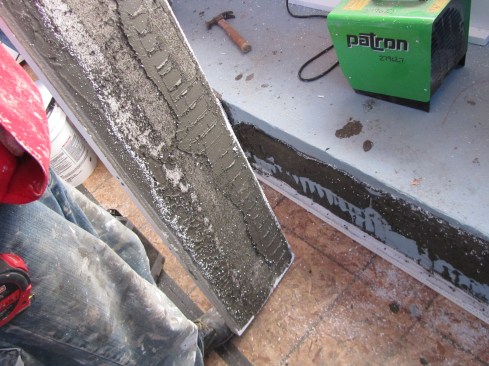 We had the crew remove the board, revealing that the vertical channels were blocked by the additional adhesive used to flatten a dip in the wall.