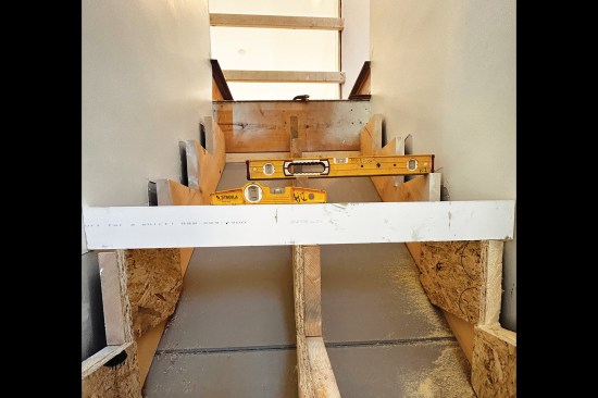 A 1-by and level are used to check the alignment of the corrective blocks across the stringers.