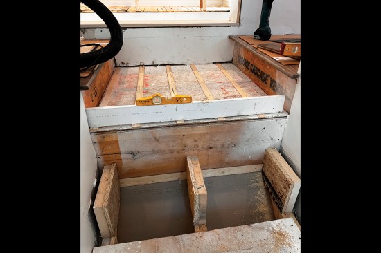 The dropped landing was out-of-level, which the author corrected with progressively thicker shims on 8-inch centers to support the oak flooring added later by the flooring installer.