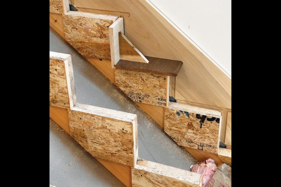 The cut-off model was used to trace the tread and riser outlines onto the skirtboards at each step. (Here, the model is used to check the routed cuts of a tread and riser on a housed skirtboard.)