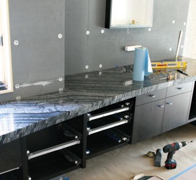 The stained maple vanity cabinet supports an 11-foot-long Kenyan marble countertop with a bookmatched front edge.