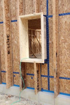 Window openings are framed out to the depth of the wood I-joists using engineered rim-board material. In this example, windows will be set flush with the outer face of the strapped wall. But in other cases, windows may be set at the center of the wall.