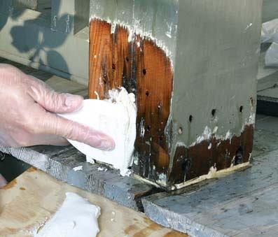 Using a plastic putty knife, the author presses the epoxy paste firmly into the crevice, then wipes the surface smooth.