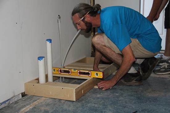 Jeff checks the box for level. The kitchen floor of the old house sags in the center and, as expected, the box is high at the back.